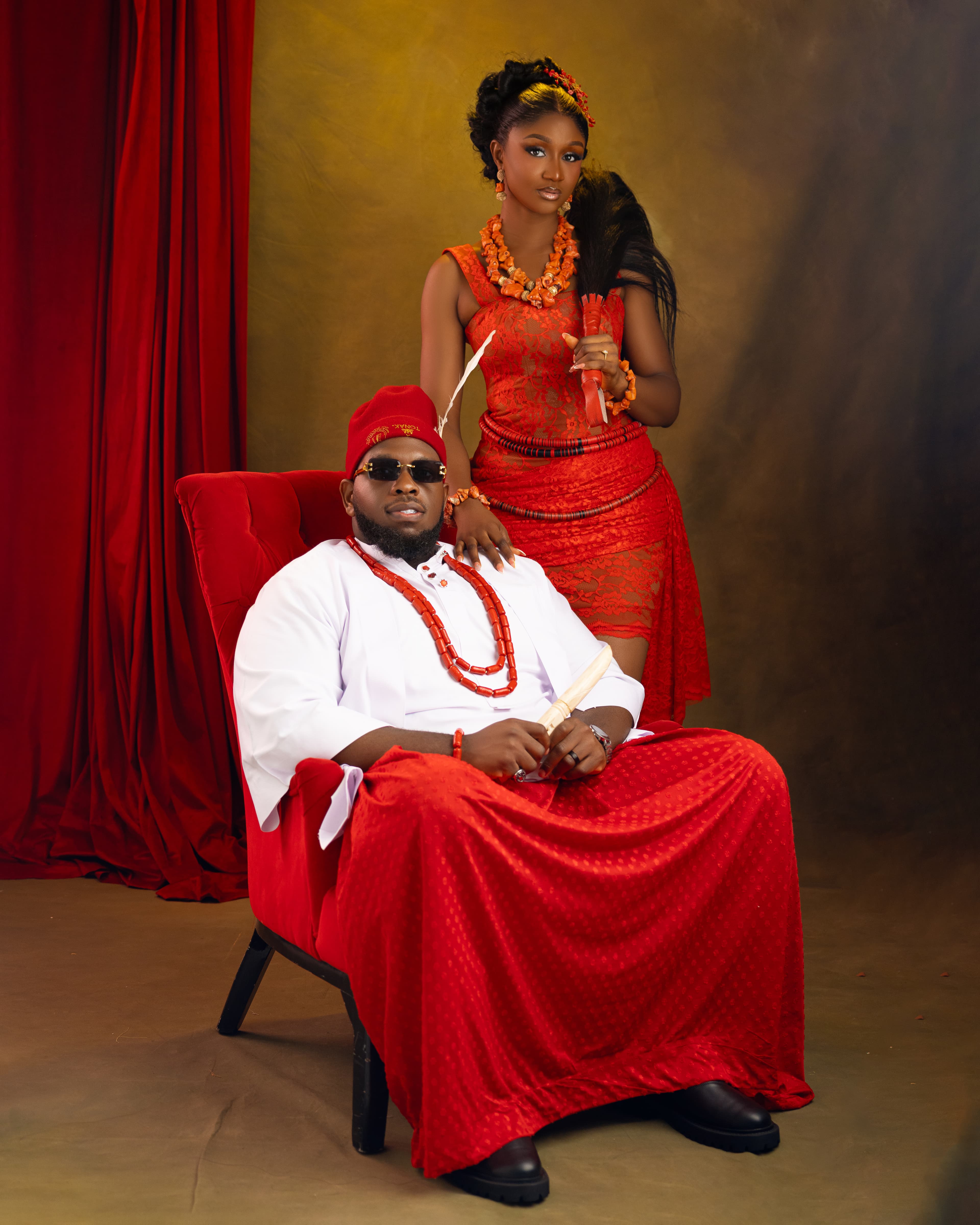 Ifeanyi seated with Gabrielle standing beside him in traditional attire